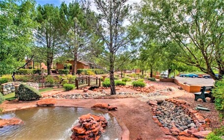 A landscaped garden with a pond, pathways, and a wooden bridge.