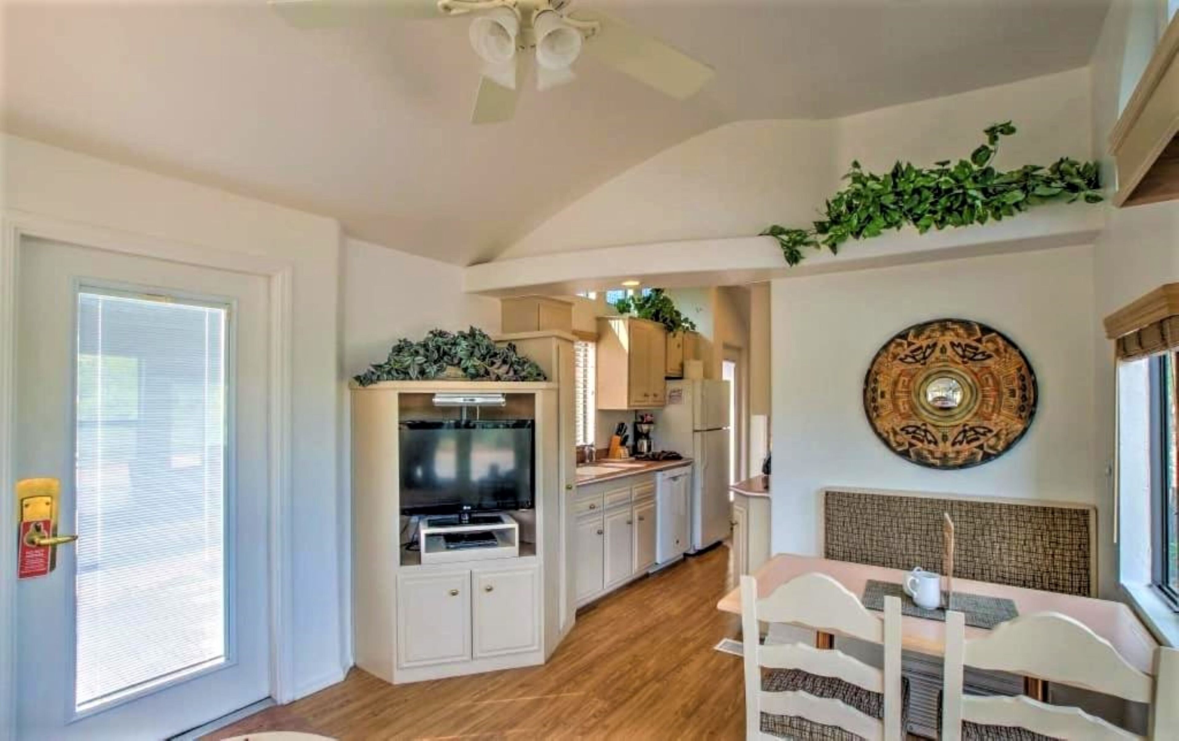 A modern kitchen with white cabinets, a built-in oven, and a dining area with a table and chairs.