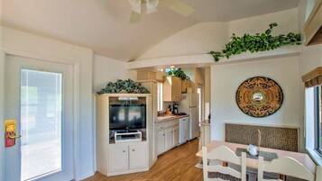 A modern kitchen with white cabinets, a built-in oven, and a dining area with a table and chairs.
