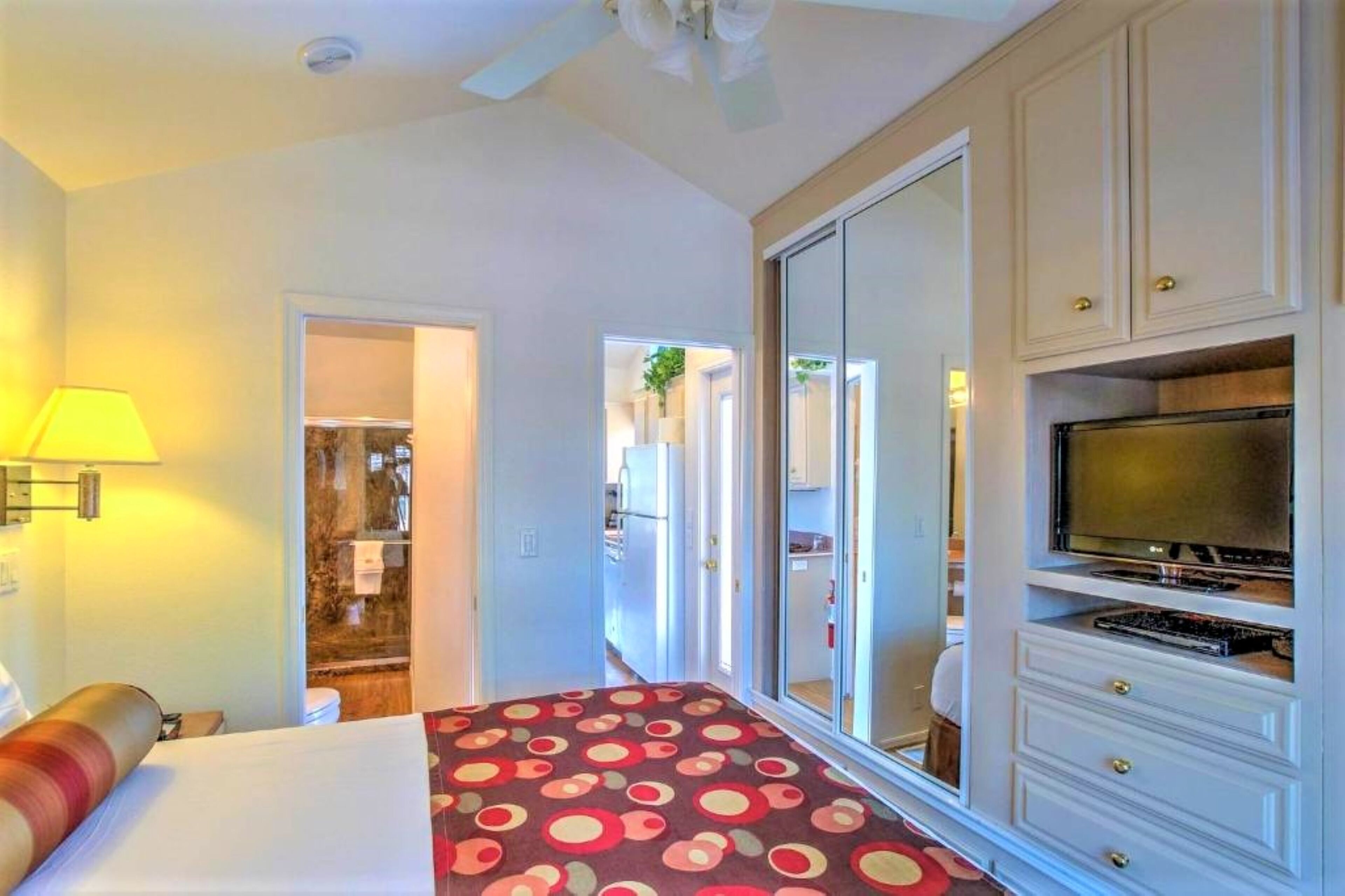 A hotel room with a bed, a TV, a wardrobe, and a bathroom visible through an open door.