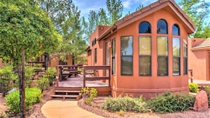 A single-story building with a curved roof, large windows, and a patio area with a wooden deck and seating. - Sedona Pines Resort (Sedona)