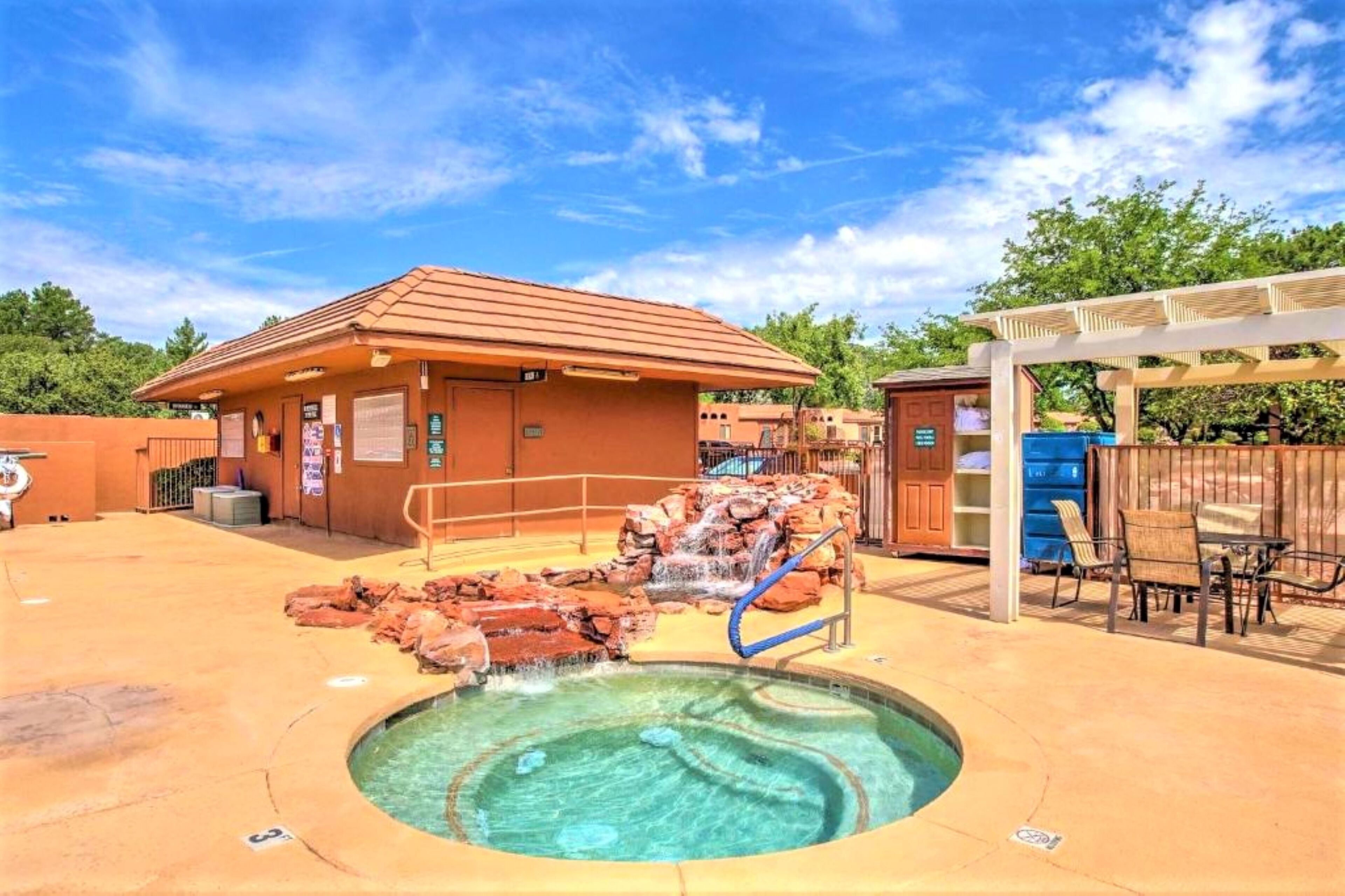 Un espace piscine comprenant un jacuzzi, une petite cascade et un coin salon abrité.