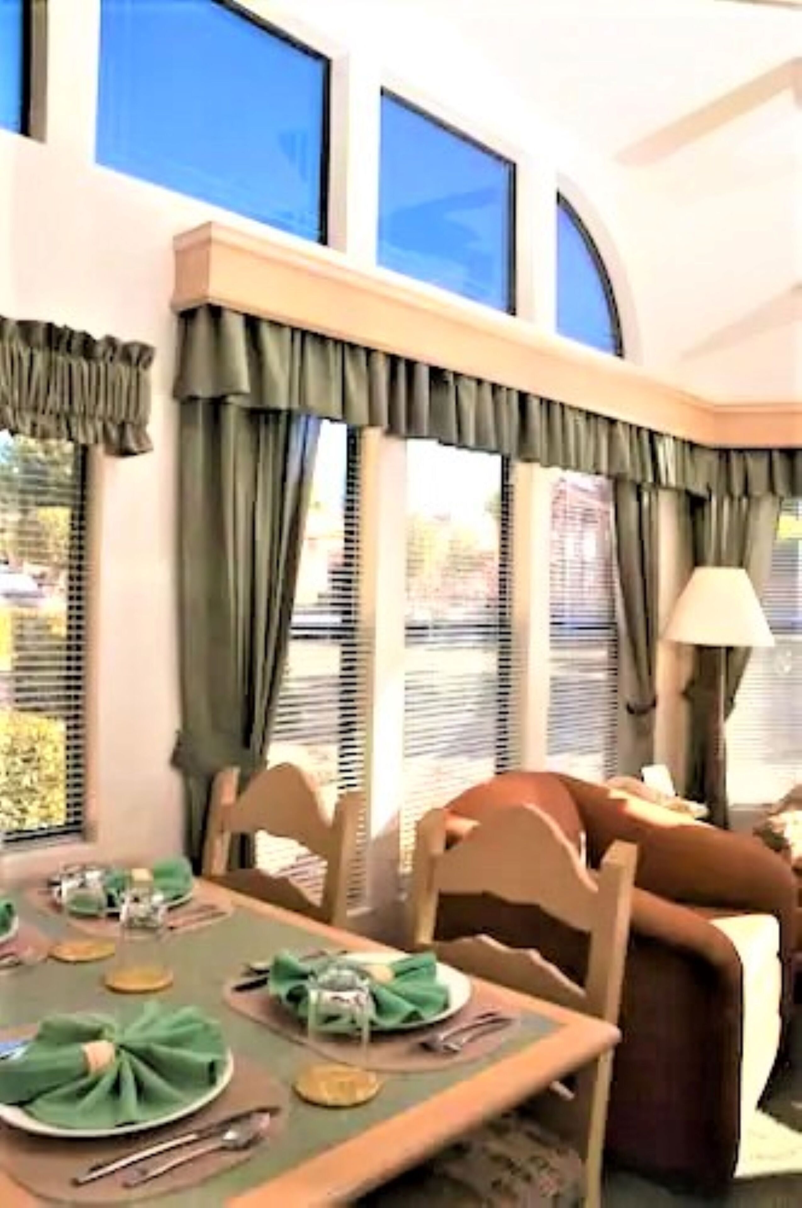 Un coin repas avec une table dressée pour quatre personnes, des chaises, une lampe et une fenêtre avec des rideaux.