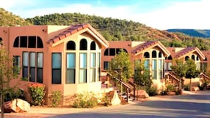 A row of modern, single-story buildings with arched windows and a uniform architectural style, set against a hilly backdrop. - Sedona Pines Resort (Sedona)