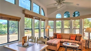 A spacious room with a large window, a ceiling fan, and a sofa with patterned cushions. - Sedona Pines Resort (Sedona)