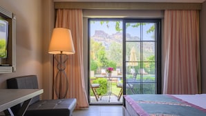 Une chambre d’hôtel équipée d’un lit, d’un bureau, d’une chaise, d’une table et offrant une vue sur l’extérieur.