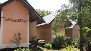 A building with a sloped roof and a garden area with various plants and trees. - Sandee Bungalows (Ko Pha-ngan)
