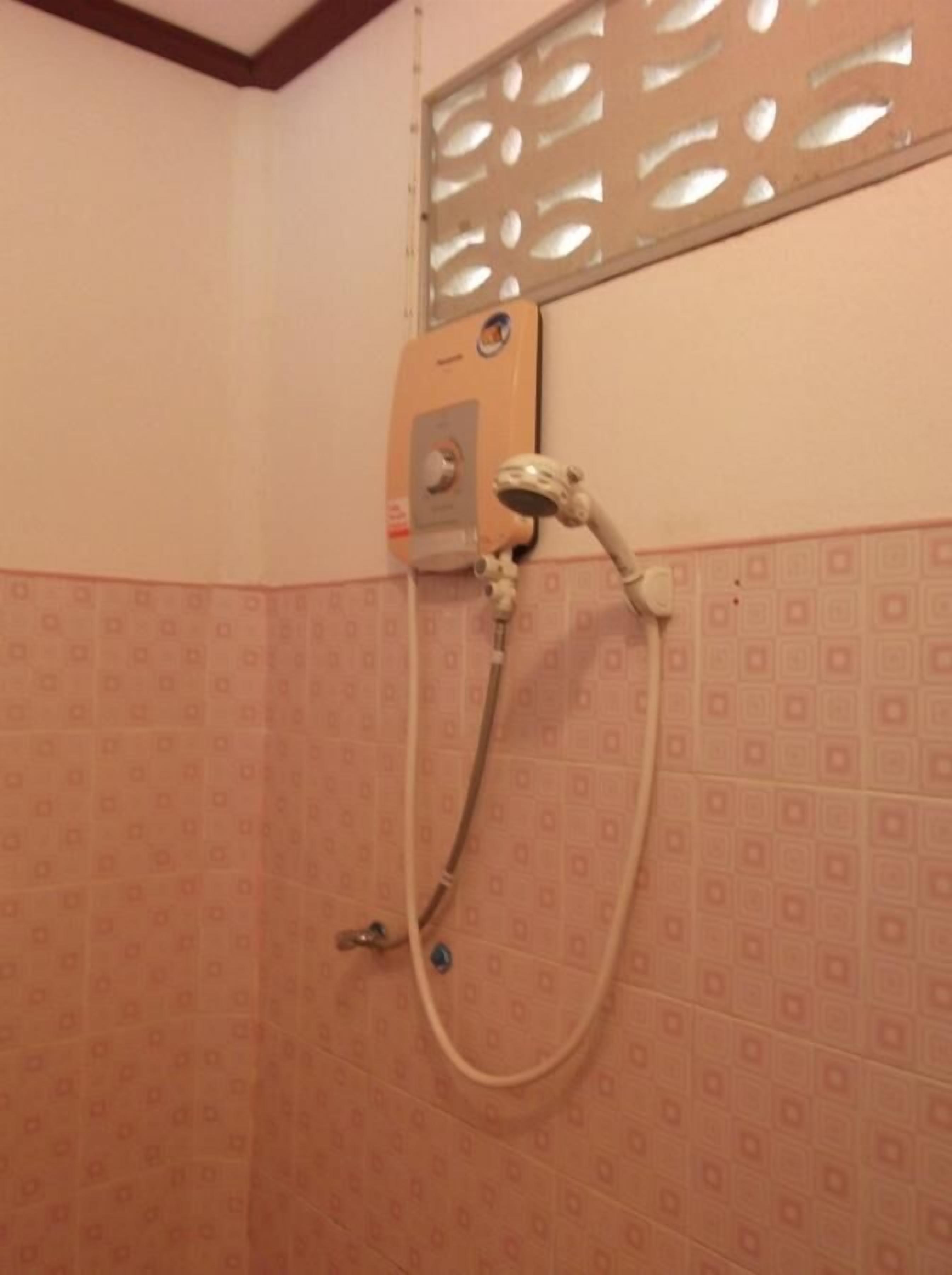 A shower with a control panel and a handheld showerhead.
