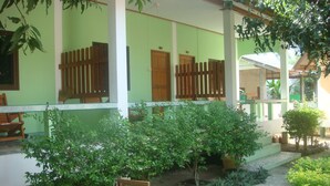 A covered outdoor area with a green wall, wooden doors, and a garden with various plants. - Sandee Bungalows (Ko Pha-ngan)