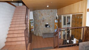 A staircase leading to a stone wall, a fireplace, and a dining area with chairs and tables. - Summit Ridge Alpine Lodge (Falls Creek)