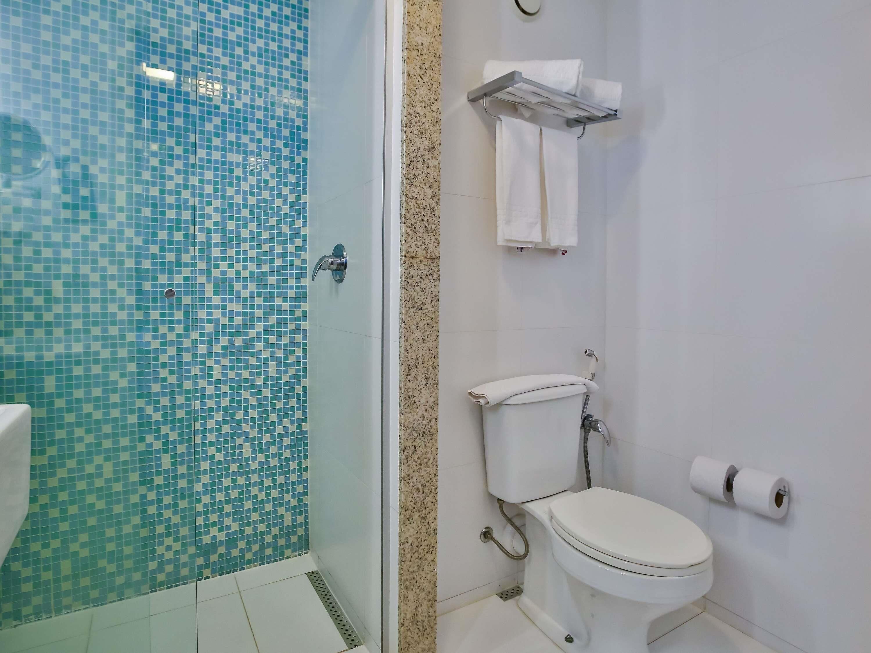 A bathroom with a tiled shower area, a toilet, and a towel rack.