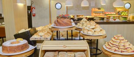 Una vitrina de panadería con diversas opciones de pan, pasteles y un pastel.