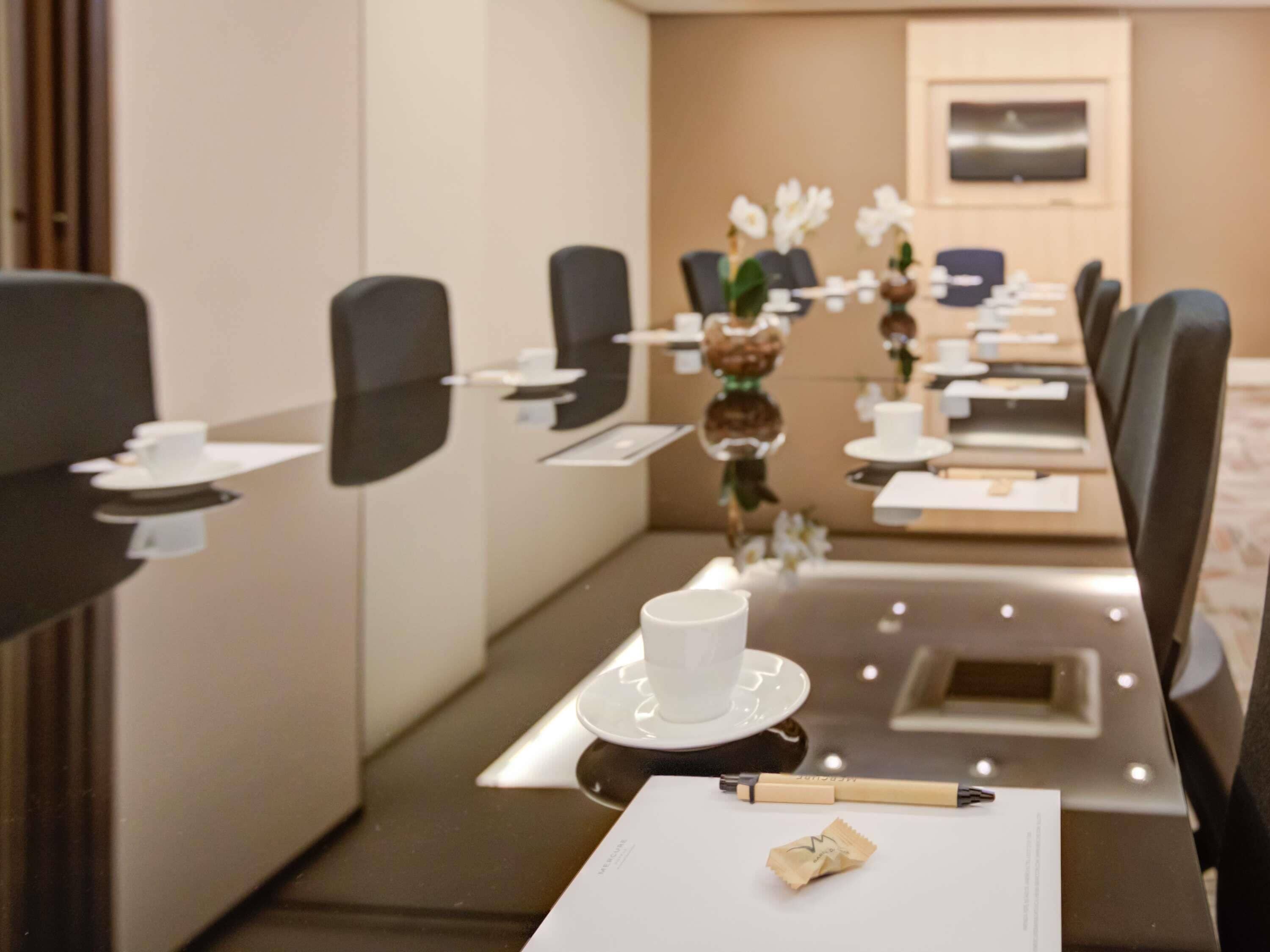 A conference room with a long table, chairs, and a television on the wall.