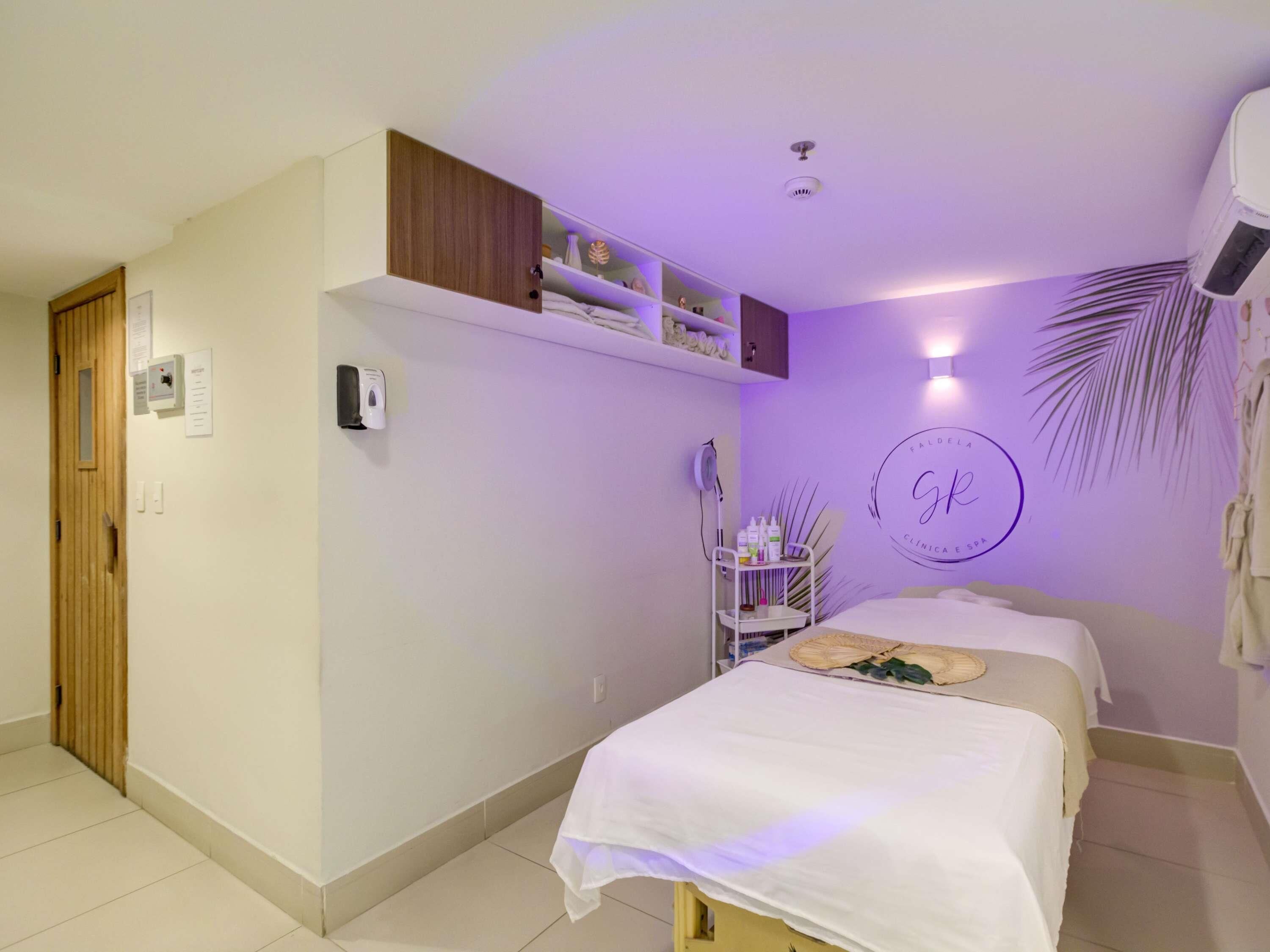 A bedroom with a bed, a shelf with toiletries, a wall-mounted air conditioner, and a door.