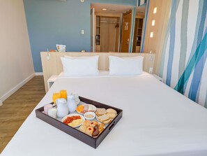 A hotel room with a bed, a tray of breakfast items, a mirror, and a wardrobe. - Mercure Rio de Janeiro Barra Da Tijuca (Rio de Janeiro)