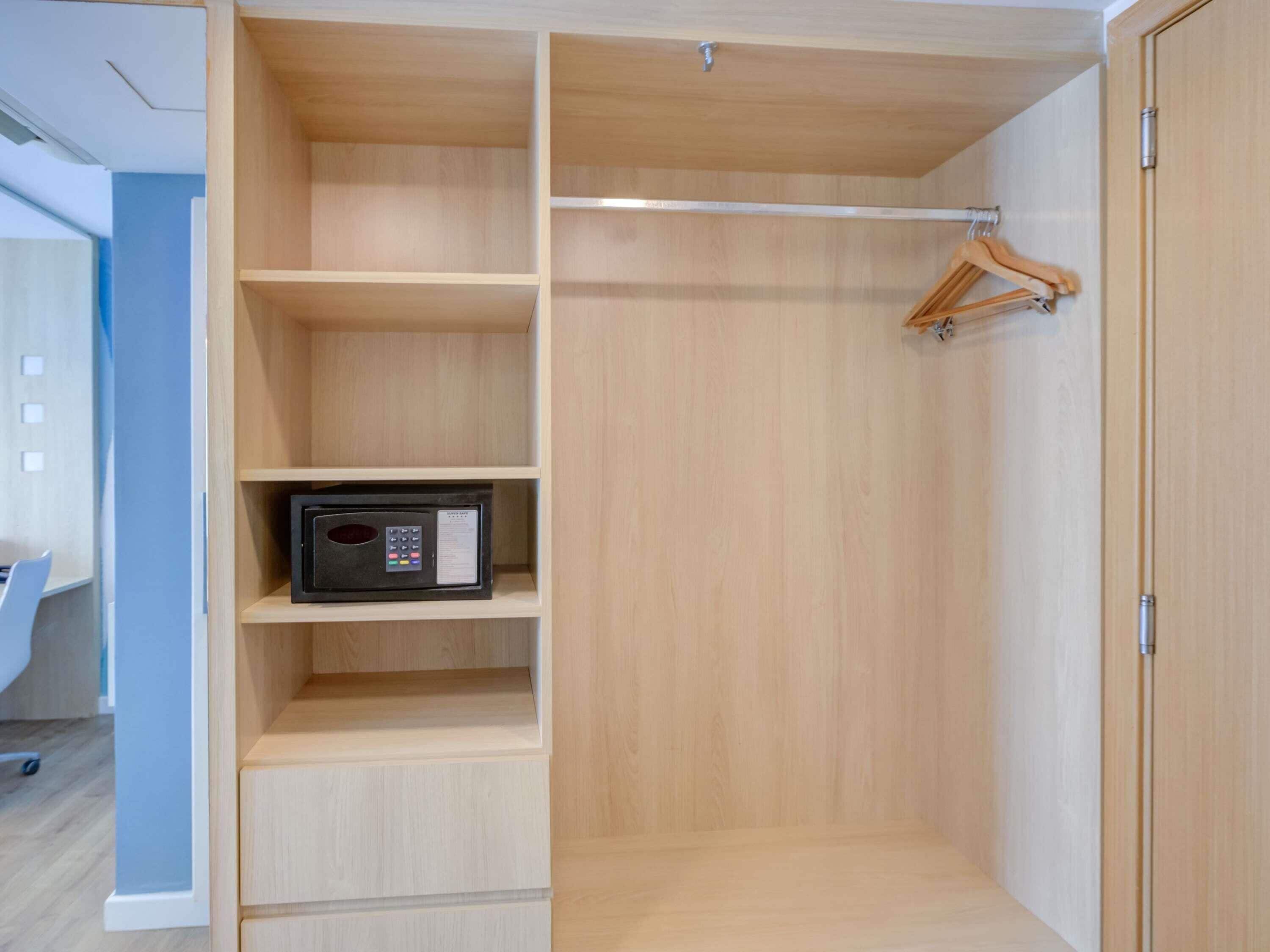 Un vestidor con estantes de madera, barra para colgar ropa y microondas.