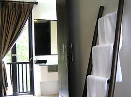 A room with a large mirror, a wardrobe, and a rack with towels.