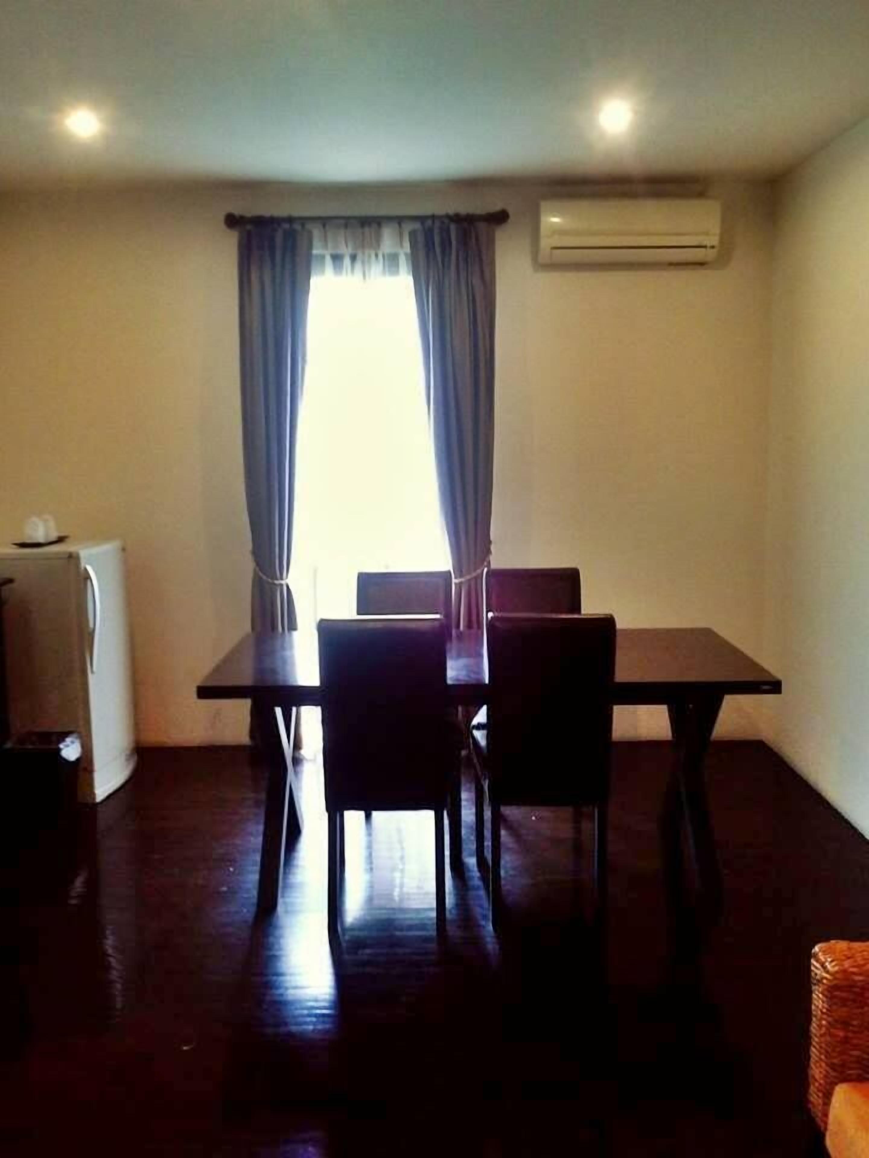 Un comedor con una mesa y sillas, una kitchenette pequeña y un equipo de aire acondicionado.
