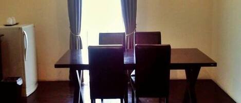 Un comedor con una mesa y sillas, una kitchenette pequeña y un equipo de aire acondicionado.