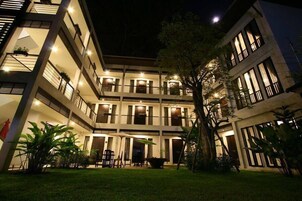 A multi-story hotel with balconies, outdoor seating, and a well-lit courtyard.