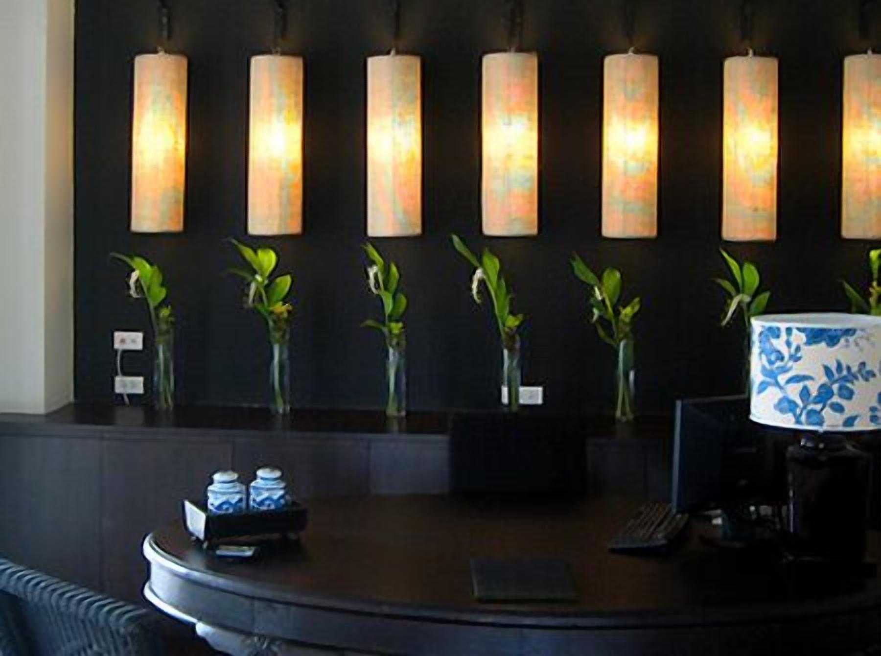 A reception area with a dark counter, six wall-mounted lamps, and small potted plants.