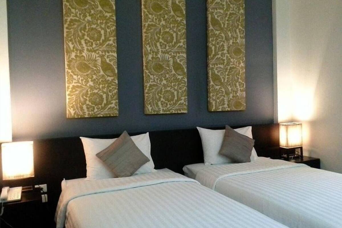 Ein Hotelzimmer mit zwei Betten, einem dunklen Kopfteil und dekorativen Wandverkleidungen.