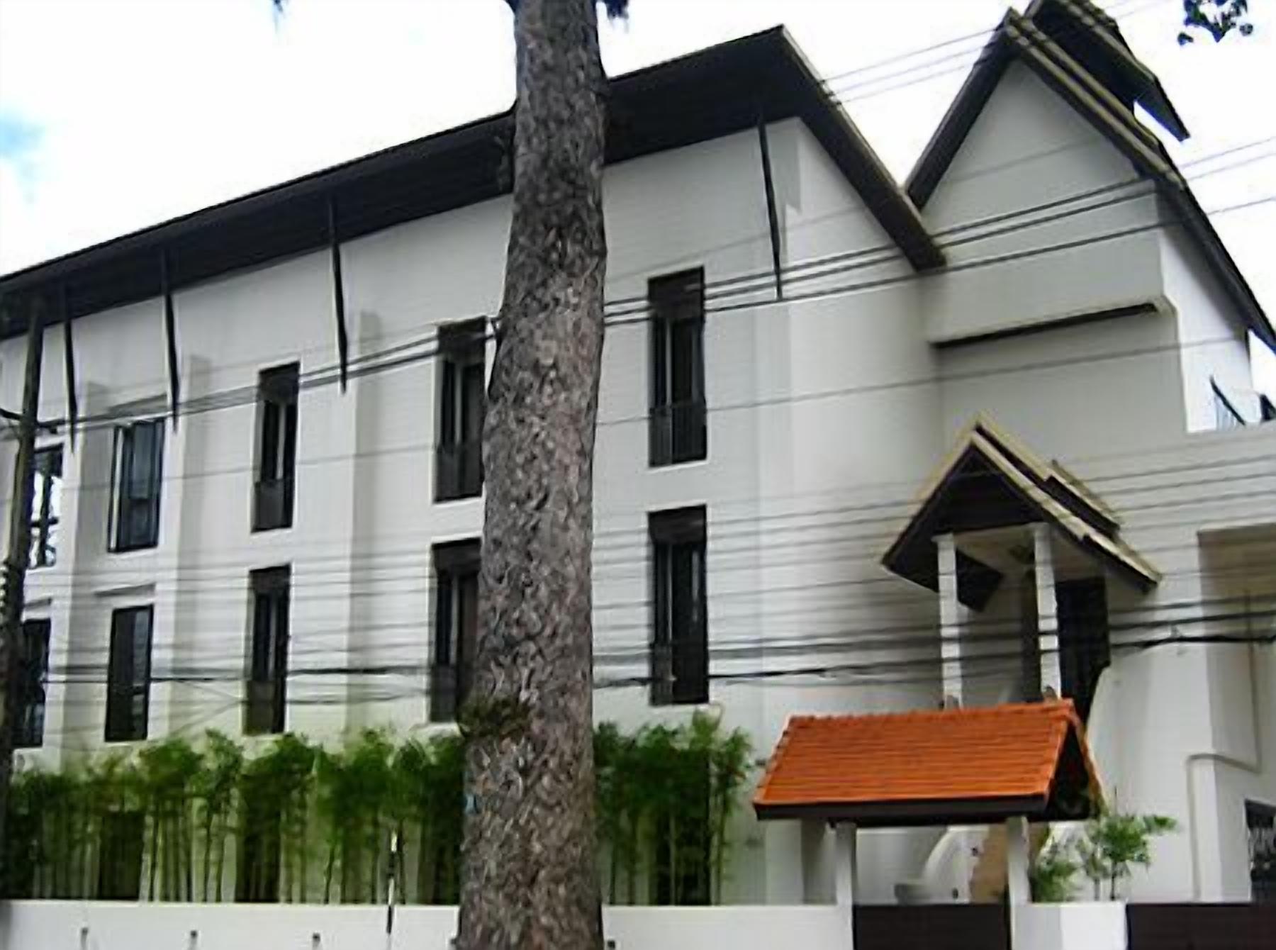 A multi-story building with a white facade, black window frames, and a red roof.