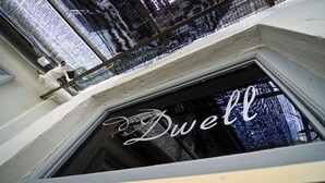 A window with the word "Dwell" in cursive, a metal railing, and a view of a snowy landscape. - Dwell by Palanquinn (George Town)