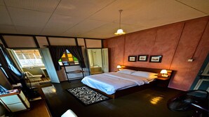 A bedroom with a bed, bedside lamps, a fan, a window with curtains, and a zebra-patterned rug. - Dwell by Palanquinn (George Town)