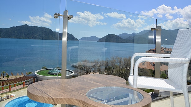 A balcony with a glass balustrade overlooking a body of water and mountains. - Green Nature Diamond Hotel (Marmaris)