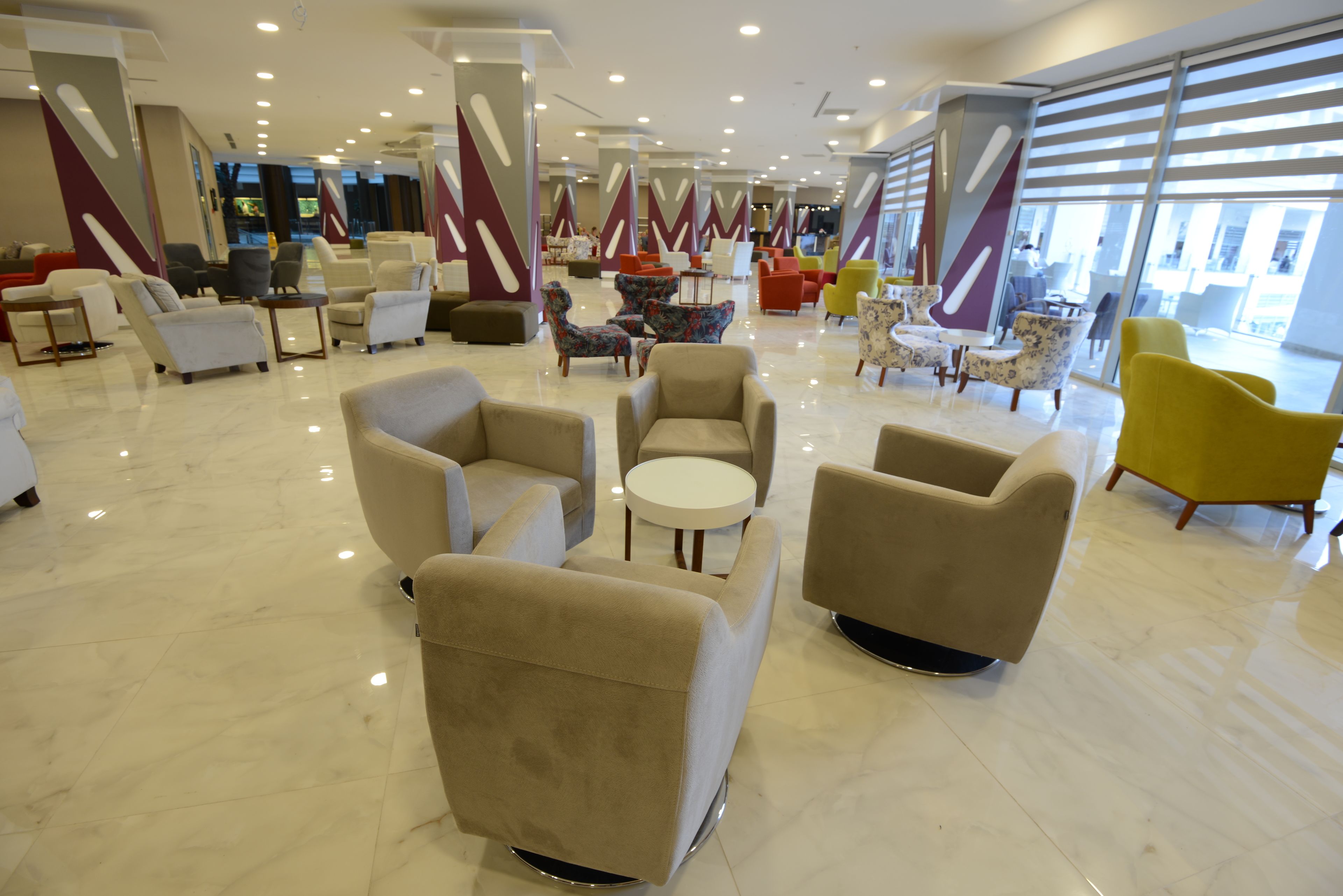Een ruime lobby met verschillende zithoeken, waaronder banken en fauteuils, gerangschikt rond een centrale salontafel.