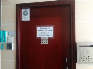 A reception sign at Flat B4, 7th Floor, with a fire door warning and a telephone with a number listed.