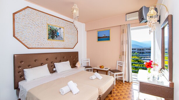 A hotel room with a large bed, a desk, and a view of the outdoors. - Minoa Hotel (Hersonissos)