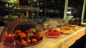 A buffet table with various food items, including fruits and desserts, covered with clear domes. - Minoa Hotel (Hersonissos)