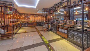 Un restaurante moderno con techo alto, tragaluces y una zona de bufé con diversas opciones de comida.
