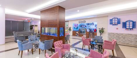 A hotel lobby with seating areas, a reception desk, and a bakery.
