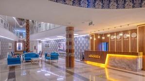 Un vestíbulo amplio con mostrador de recepción, sofás azules y un pilar decorativo.