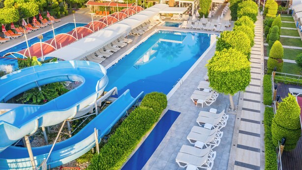 Una piscina grande con tobogán de agua, tumbonas y una zona de estar cubierta.