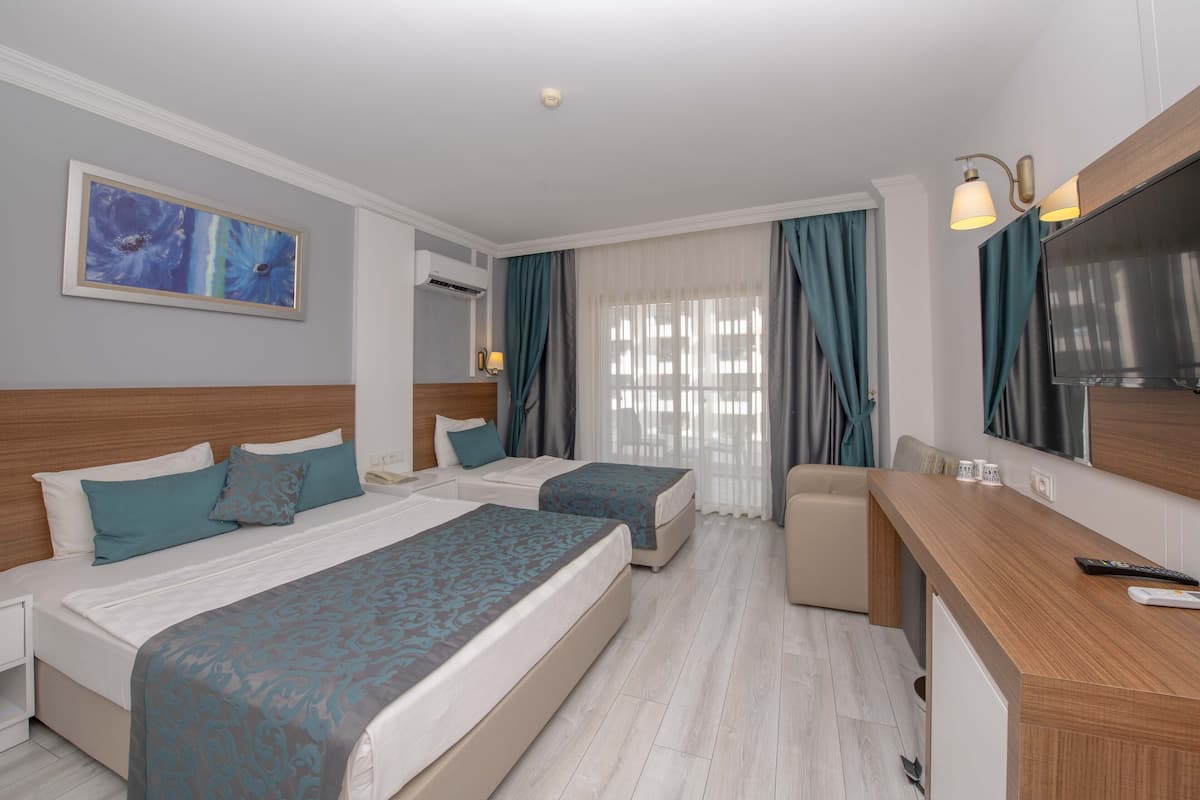 A hotel room with two beds, a desk, a TV, and a painting on the wall.