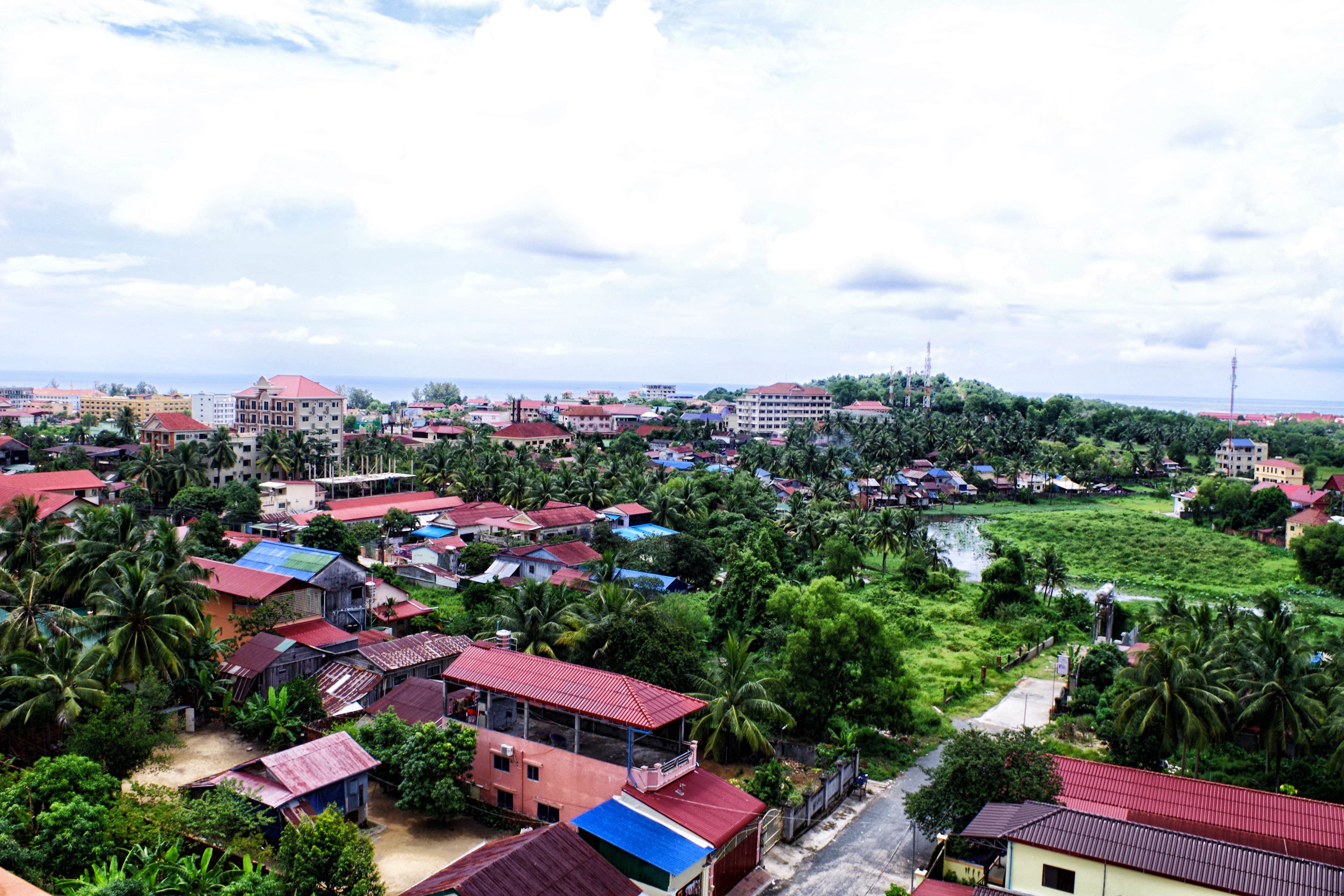 A residential area with houses, some with red roofs, surrounded by greenery and a river.