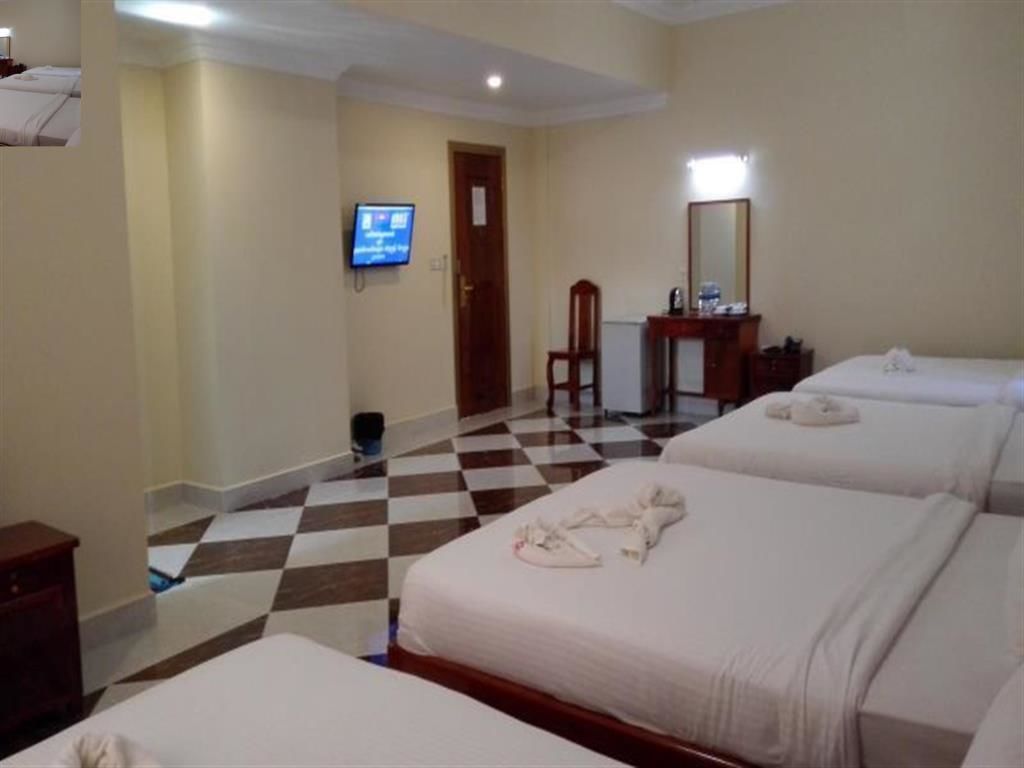 A hotel room with three beds, a television, a desk, and a chair.