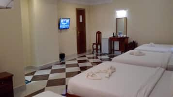 A hotel room with three beds, a television, a desk, and a chair.