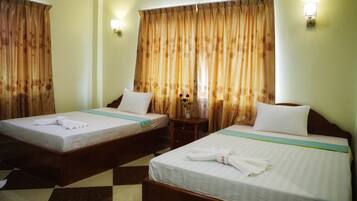 Two single beds with wooden frames, white linens, and a checkered floor pattern.