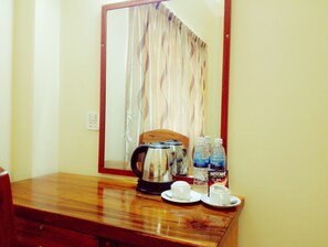 A wooden table with a kettle, two cups, and bottled water. - Golden Star Inn (Sihanoukville)