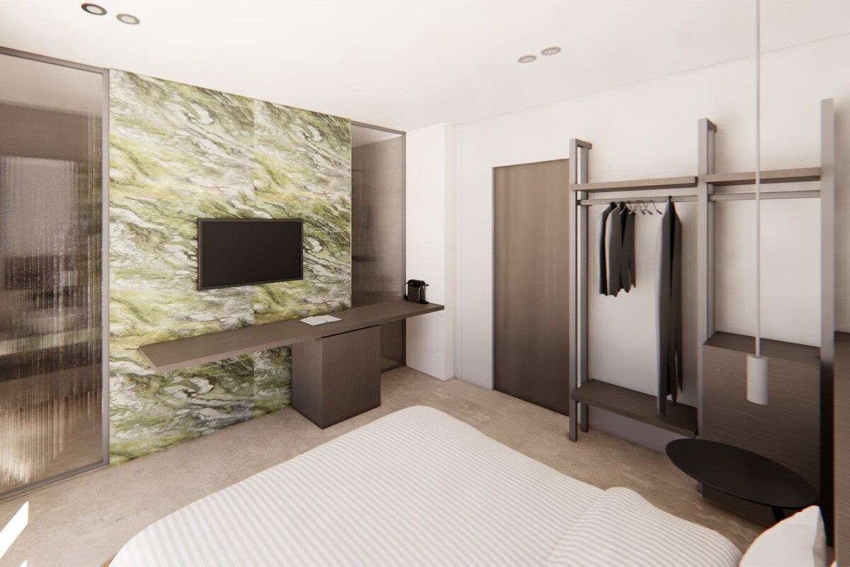 Un baño moderno con pared de mármol, televisor integrado, tocador y zona de ducha.