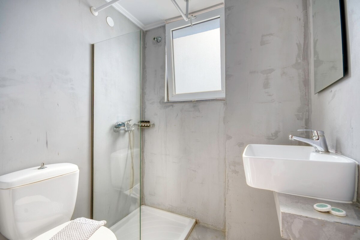 Un baño con cabina de ducha de vidrio, un lavabo blanco y un inodoro.
