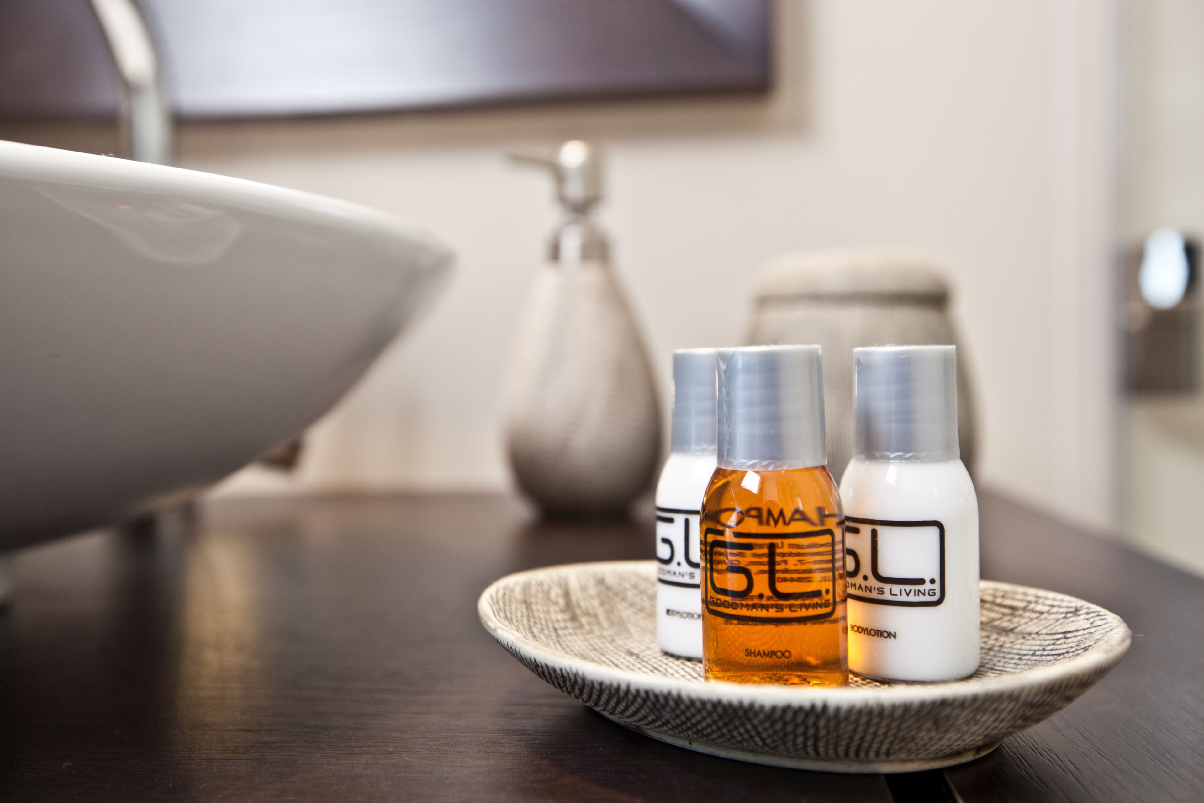 Un bagno con un lavandino, uno specchio e due flaconi di shampoo su un vassoio.
