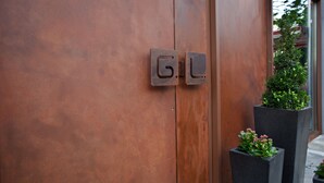 Una porta in legno con una maniglia metallica e due fioriere rettangolari con piante verdi.