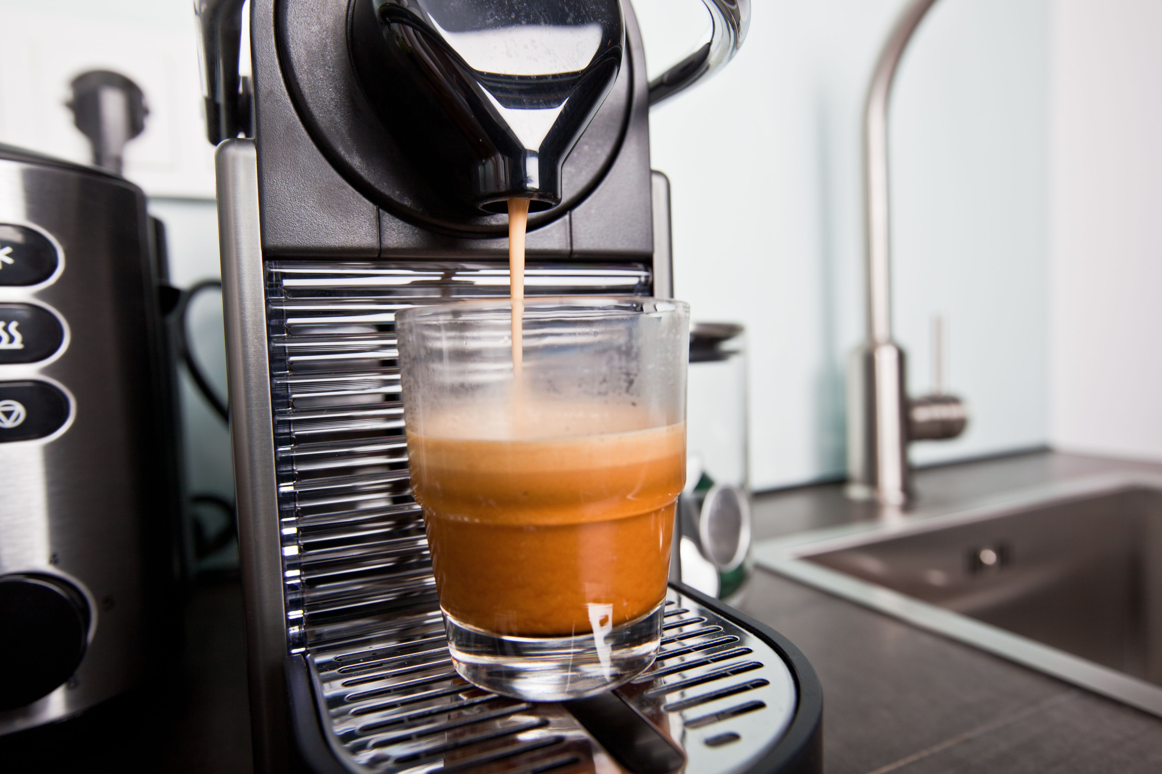 A coffee machine dispensing coffee into a clear glass cup.
