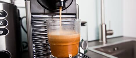 A coffee machine dispensing coffee into a clear glass cup.